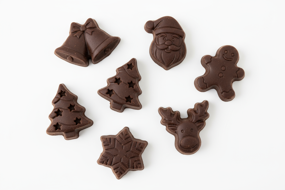 Small  chocolates, in the shape of Christmas figurines in 2-D. About 3 to 4 cm big in the shape of Christmas bells, Christmas trees, Christmas, Santas and other Christmas figurines. Dark chocolate, no colors white background.